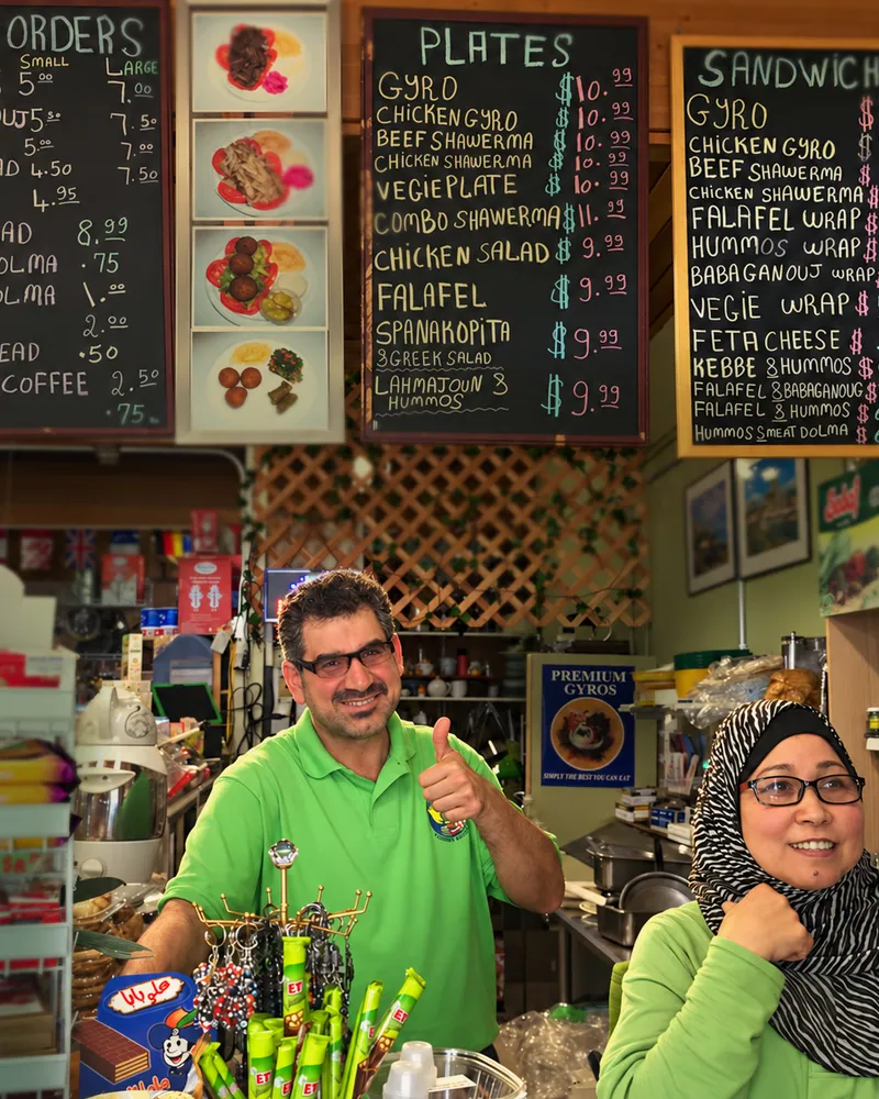 Gloria and Adil at the counter, in front of the menu boards